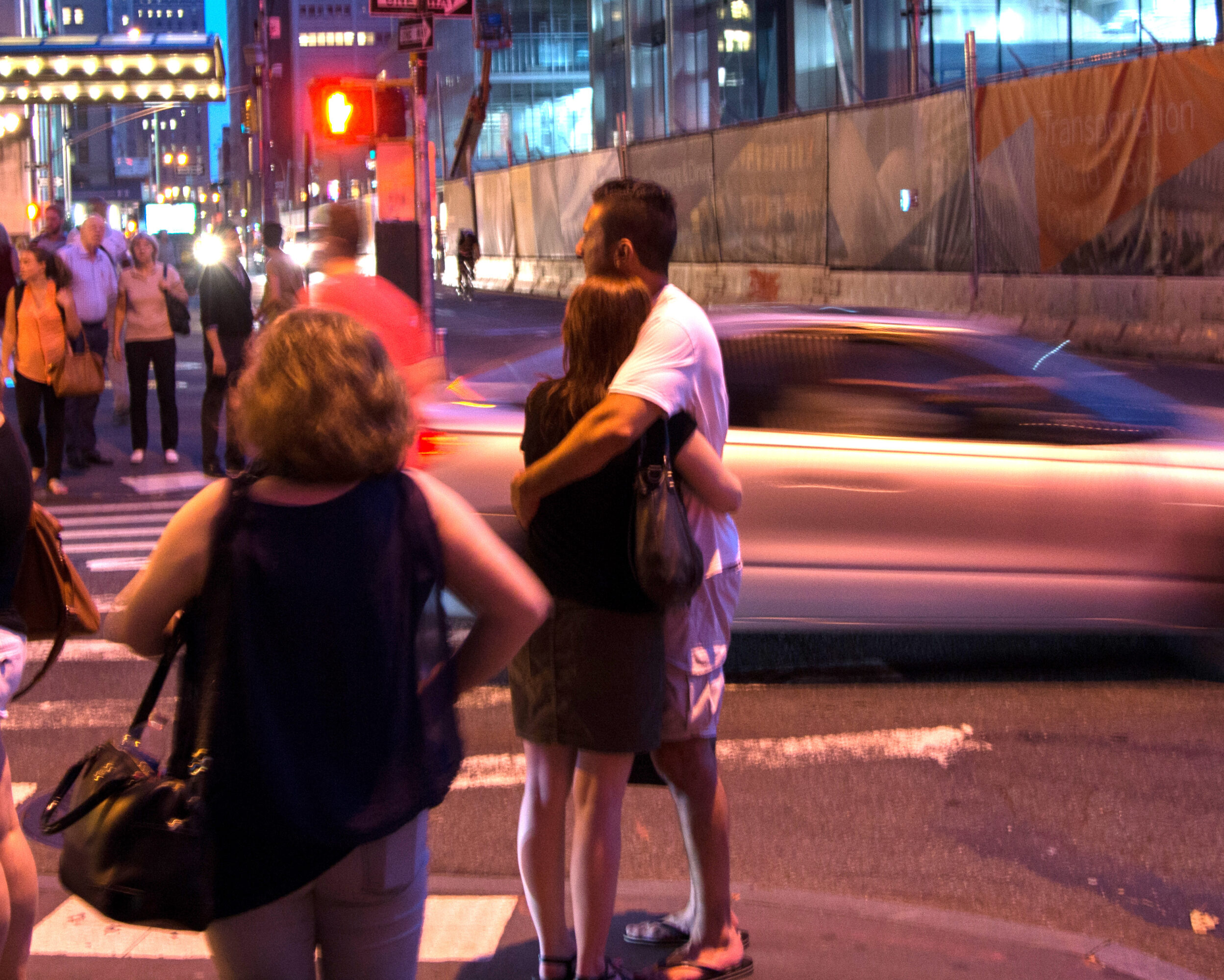 Young couple embracing at night on a street corner in lower Manhattan.